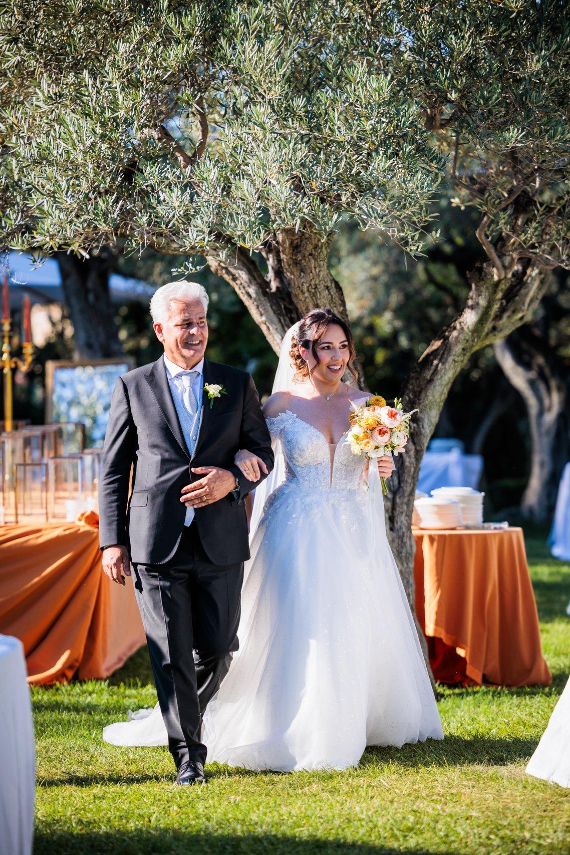 sposa a braccetto con il padre durante il corteo nuziale