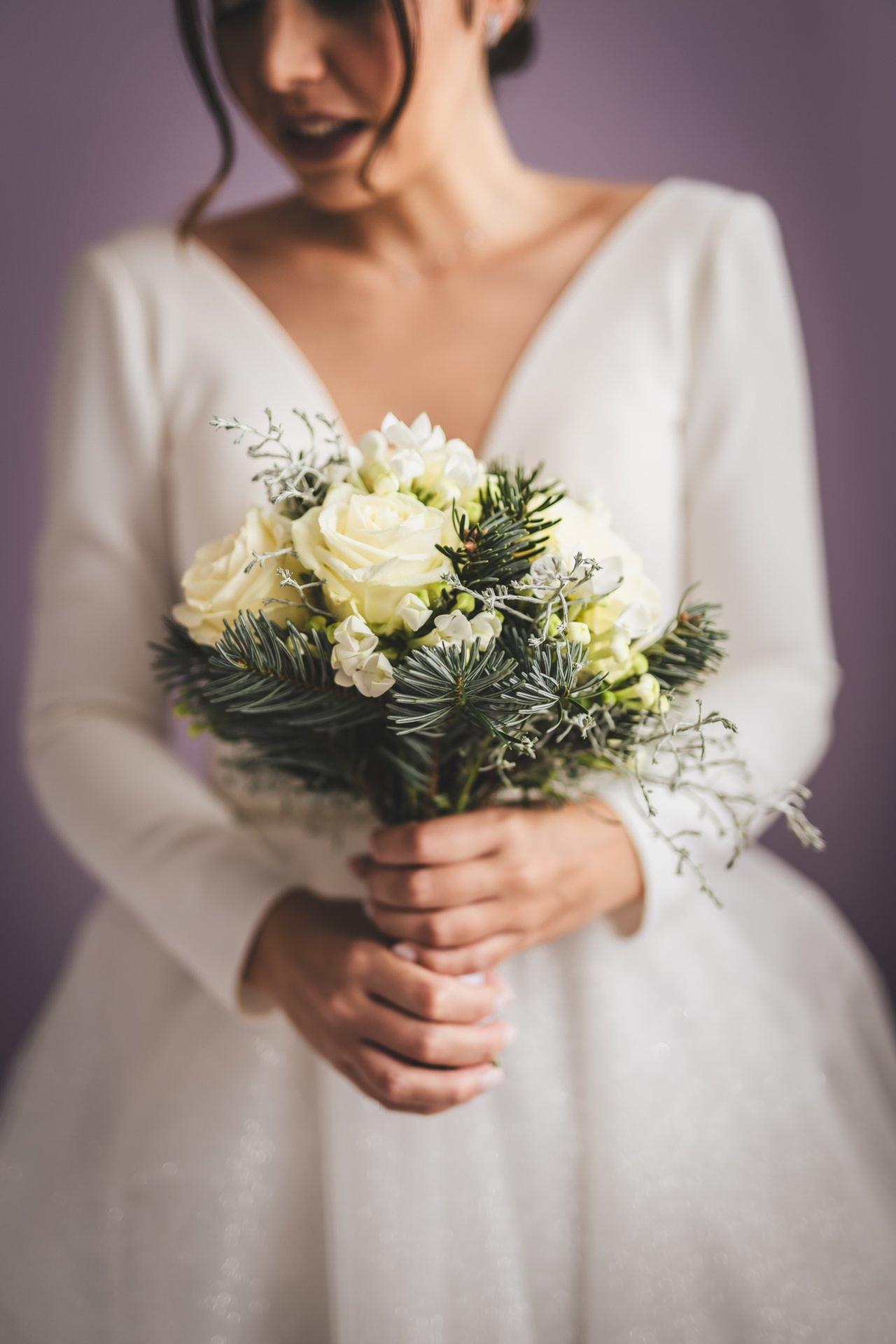 sposa che tiene in mano il bouquet autunnale in total white