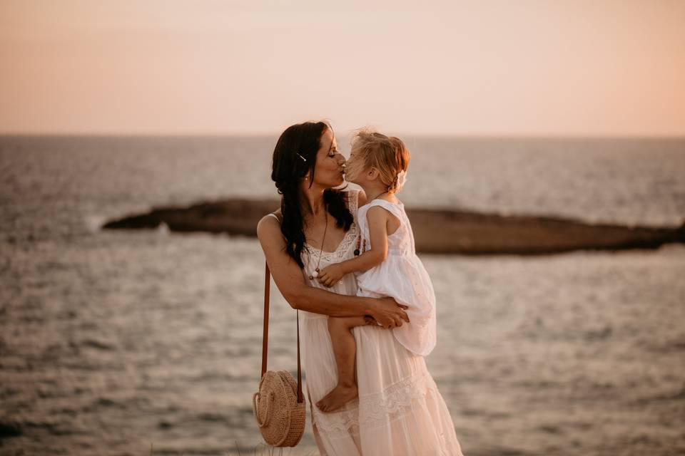 madre che bacia la figlia sulla spiaggia