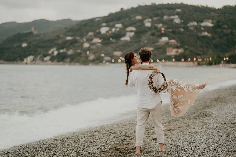 sposo che tiene in braccio la sposa su una spiaggia