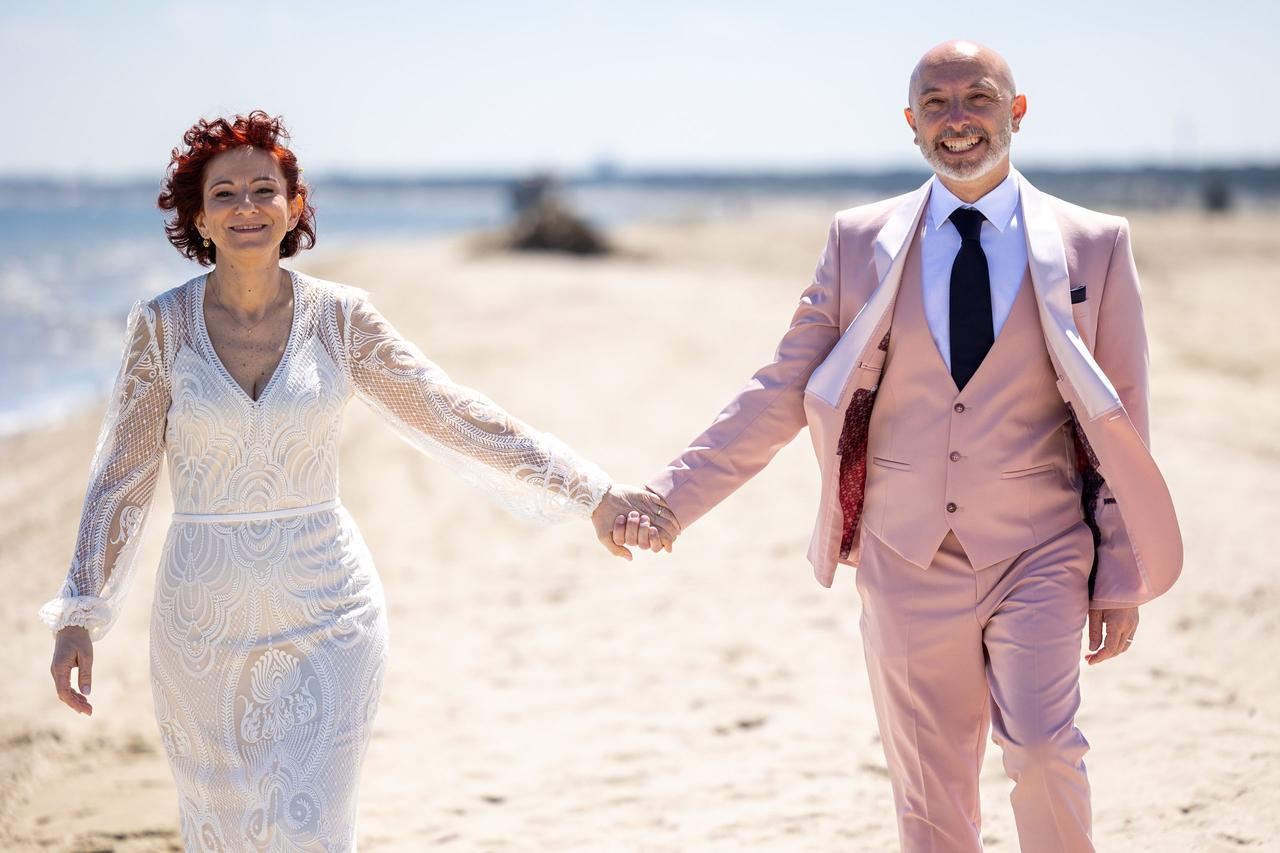 sposi mano nella mano in spiaggia