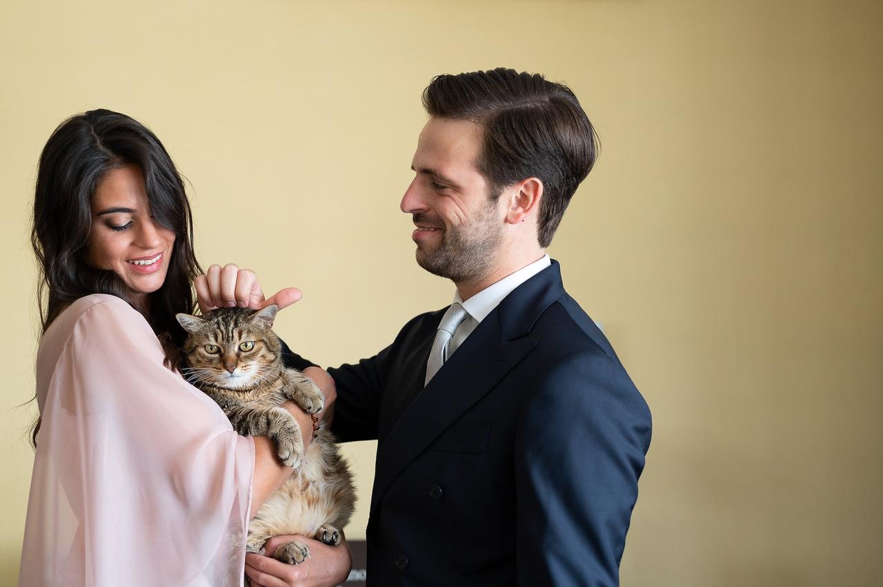 sposo che accarezza un gatto in braccio alla sposa