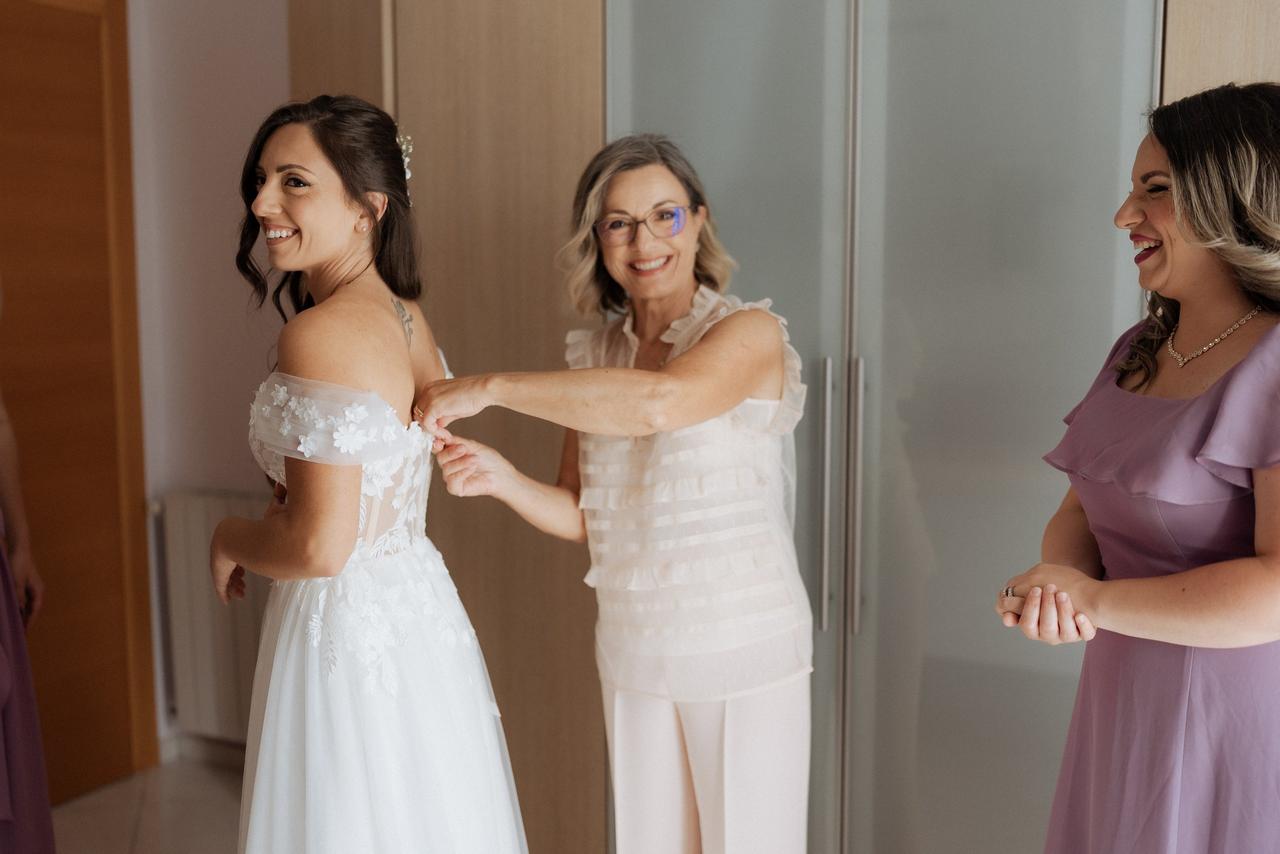 mamma della sposa che abbottona il vestito