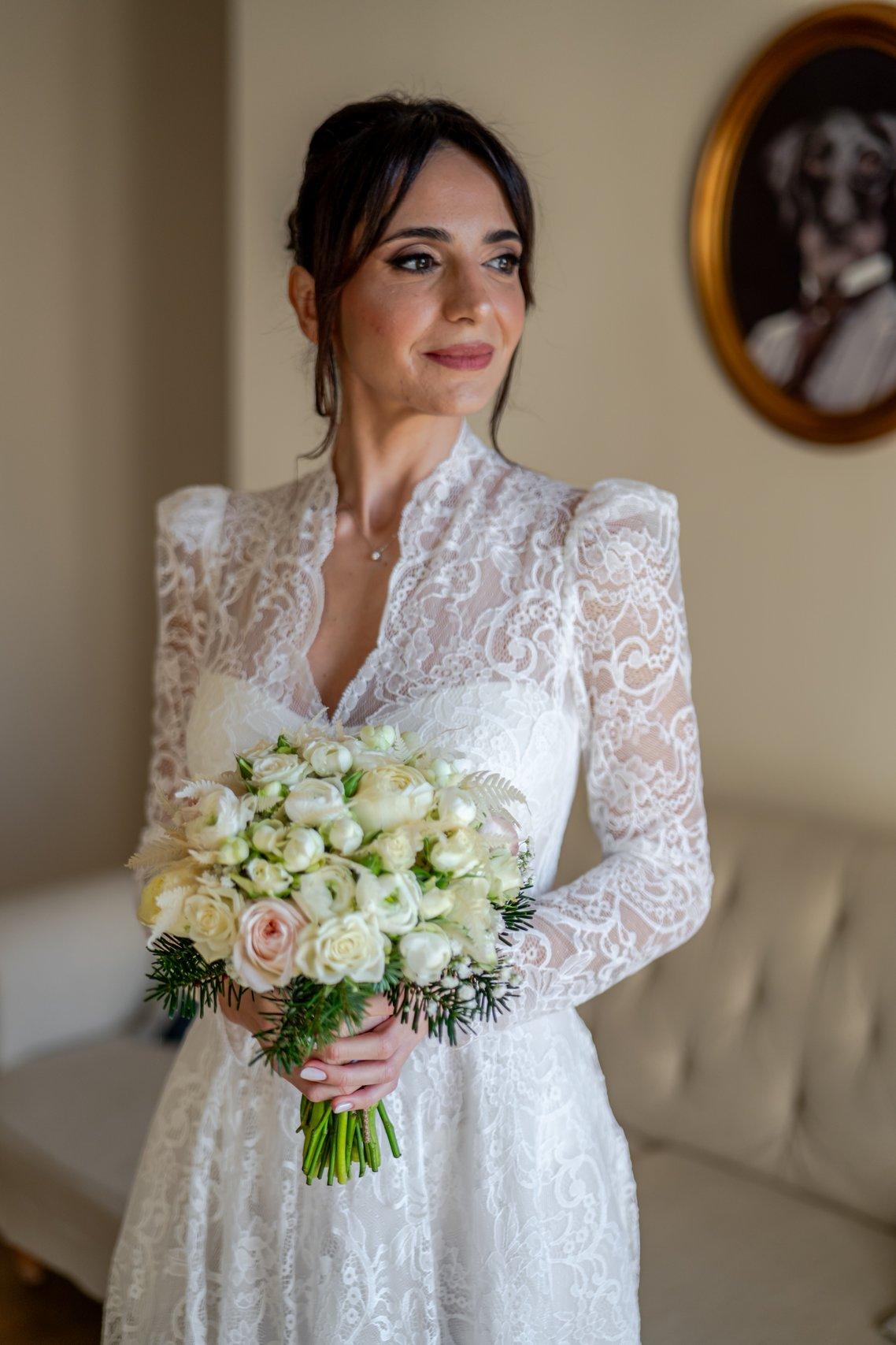 sposa che tiene in mano il bouquet da sposa invernale in total white