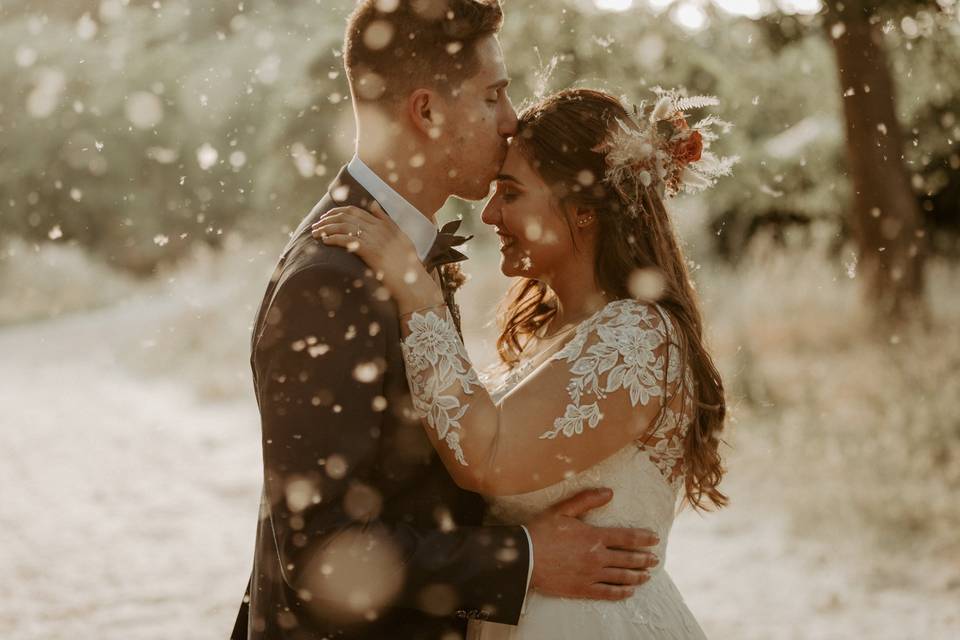 sposo che bacia sposa sulla fronte sotto la neve
