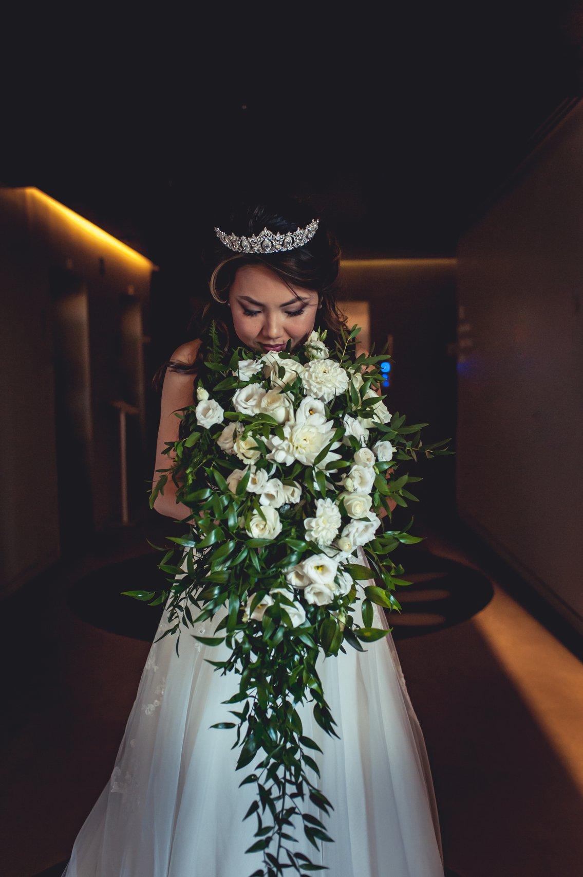 sposa che odora il suo bouquet a cascata