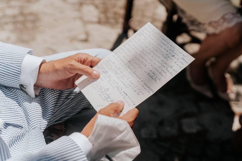 dettaglio mani sposo con in mano la lettera con le promesse matrimonio