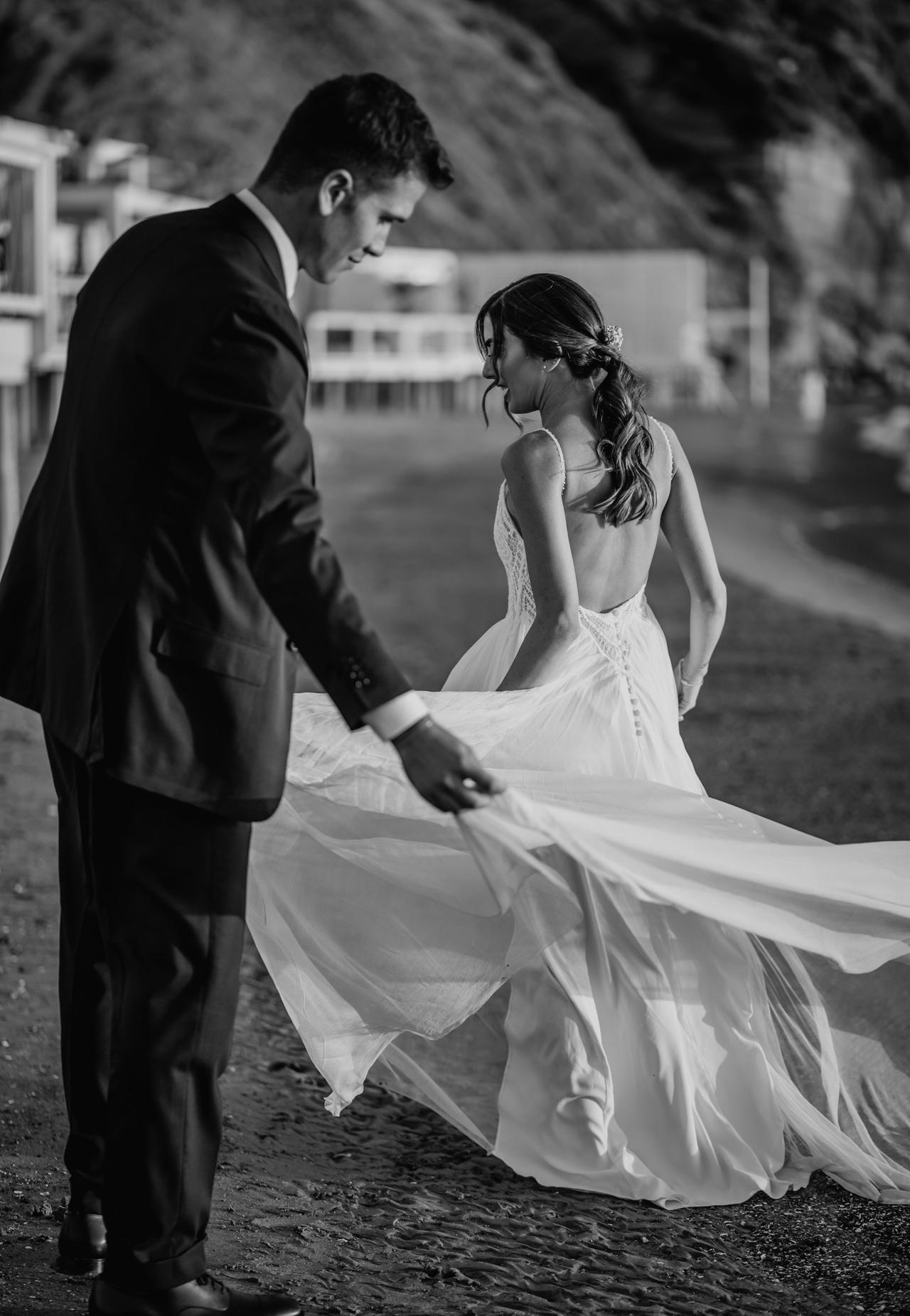 sposo che aiuta la sposa con lo strascico abito da sposa
