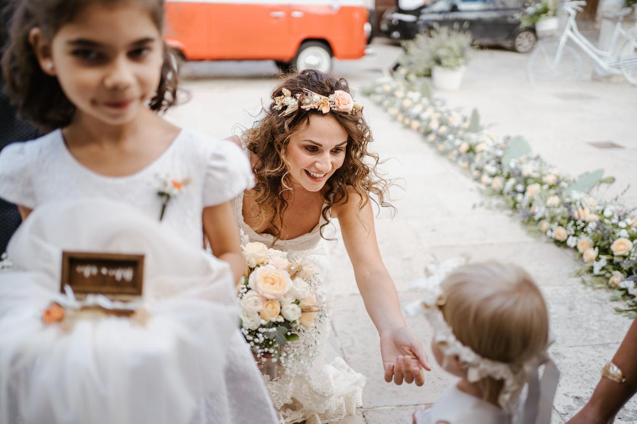 sposa che prima di entrare in chiesa sorride a una damigella bambina