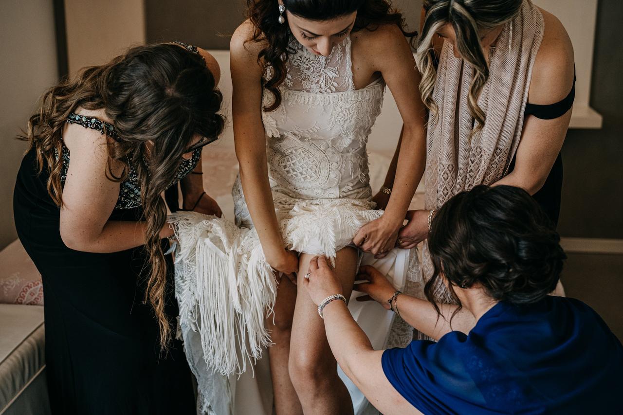 sposa che si veste aiutata dalle amiche