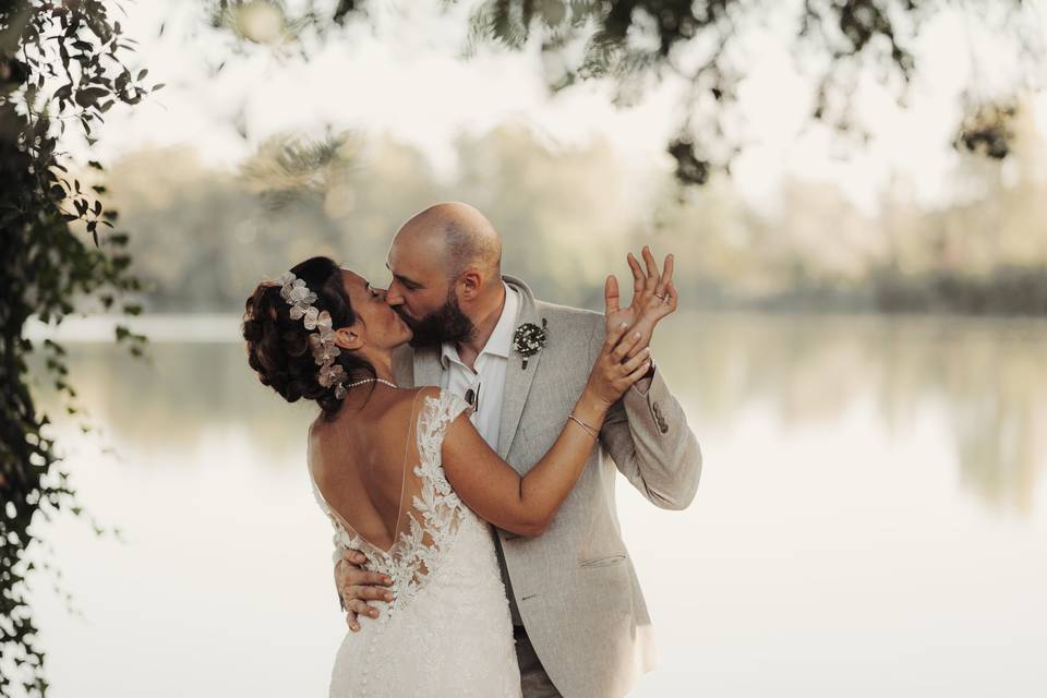 sposi che si baciano davanti a un lago