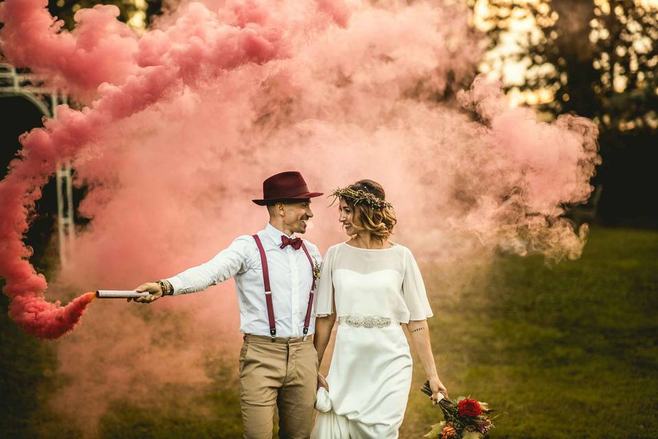 coppia di sposi con fumogeno rosa in giardino