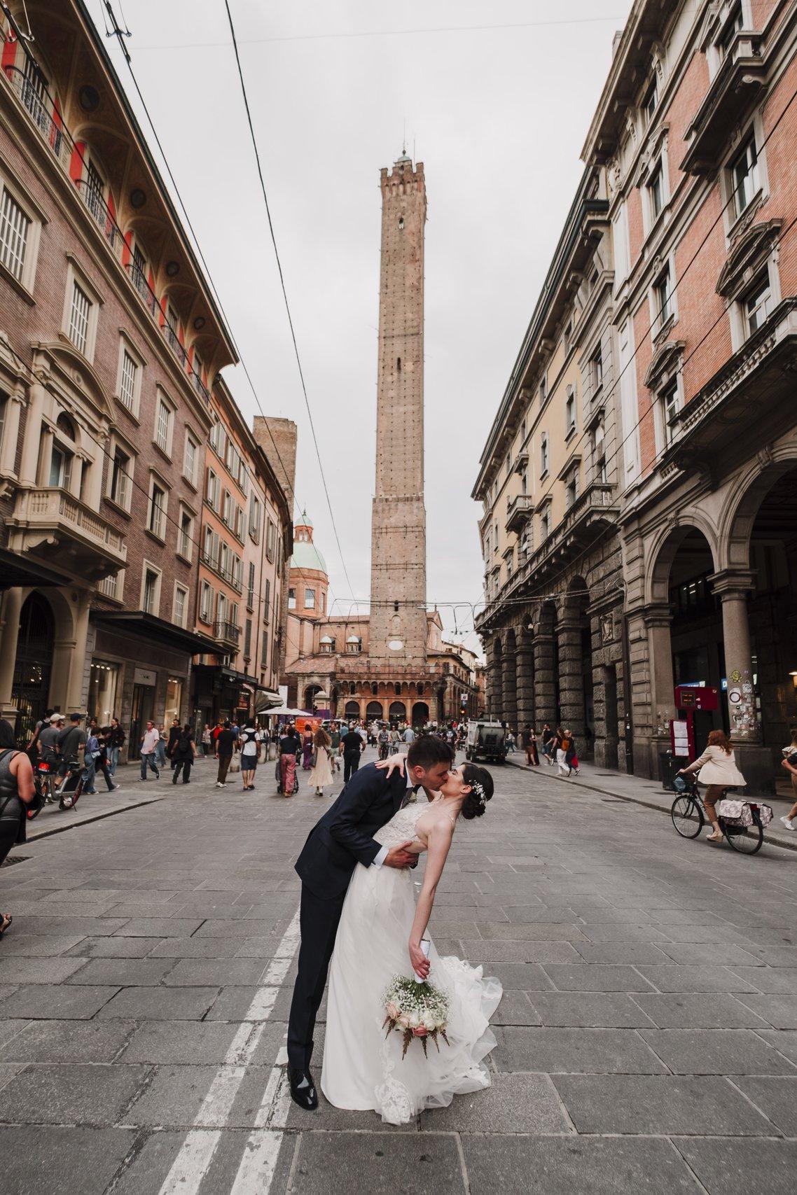 sposi che si baciano di fronte la Torre degli Asinelli a Bologna- viaggio di nozze Italia 