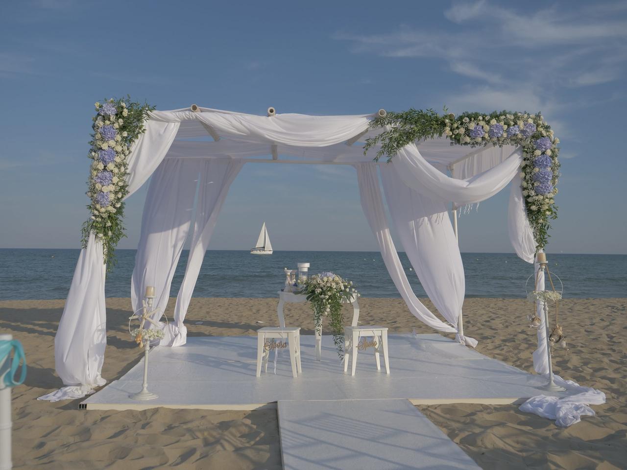 allestimento per cerimonia in spiaggia con tessuti bianchi e fiori- sposarsi al mare
