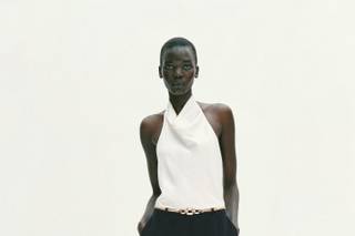 Tuta elegante da cerimonia con top bianco e pantaloni neri, scollo all'americana e schiena scoperta, cintura dorata, pantalone ampio