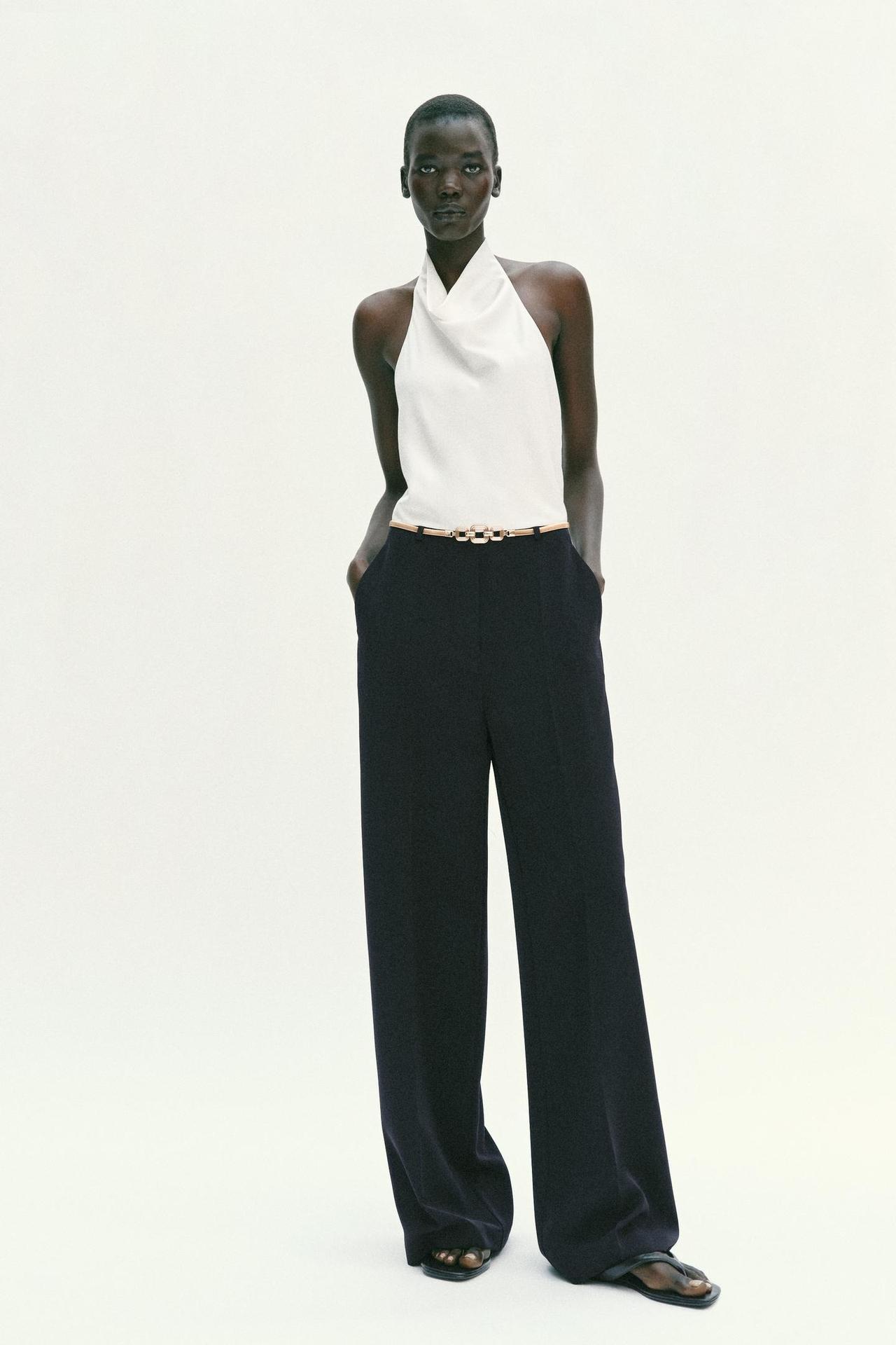 Tuta elegante da cerimonia con top bianco e pantaloni neri, scollo all'americana e schiena scoperta, cintura dorata, pantalone ampio