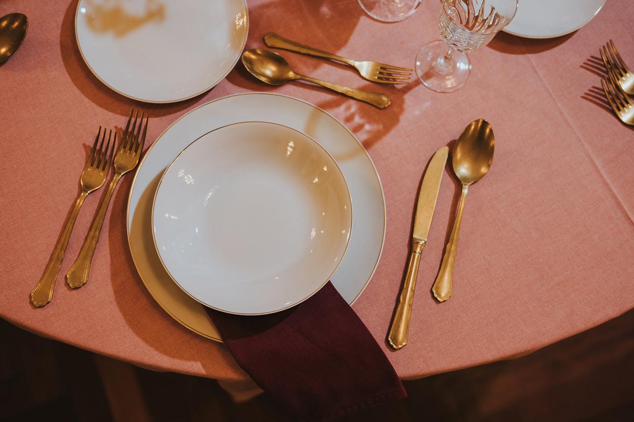 mise en place in stile regency con tovagliato rosa, porcellane bianche e oro e posate dorate
