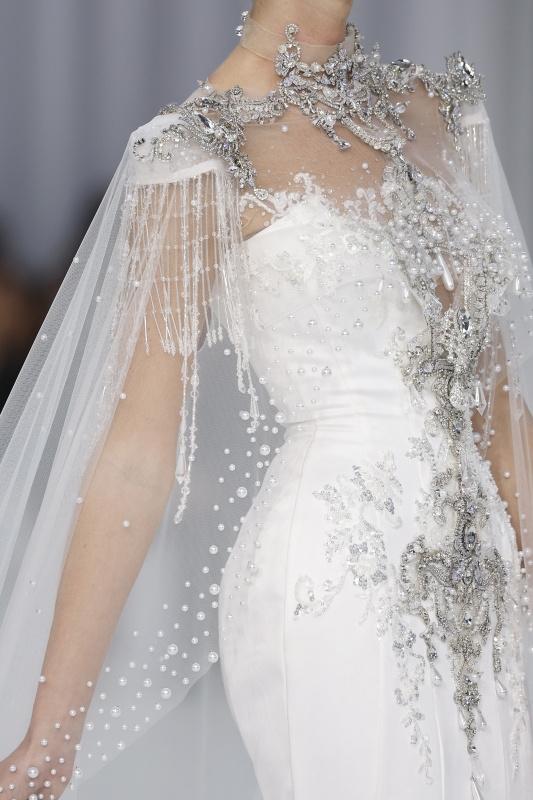 abito da sposa invernale con mantella in tulle trasparente tempestata di pietre, brillanti e perle