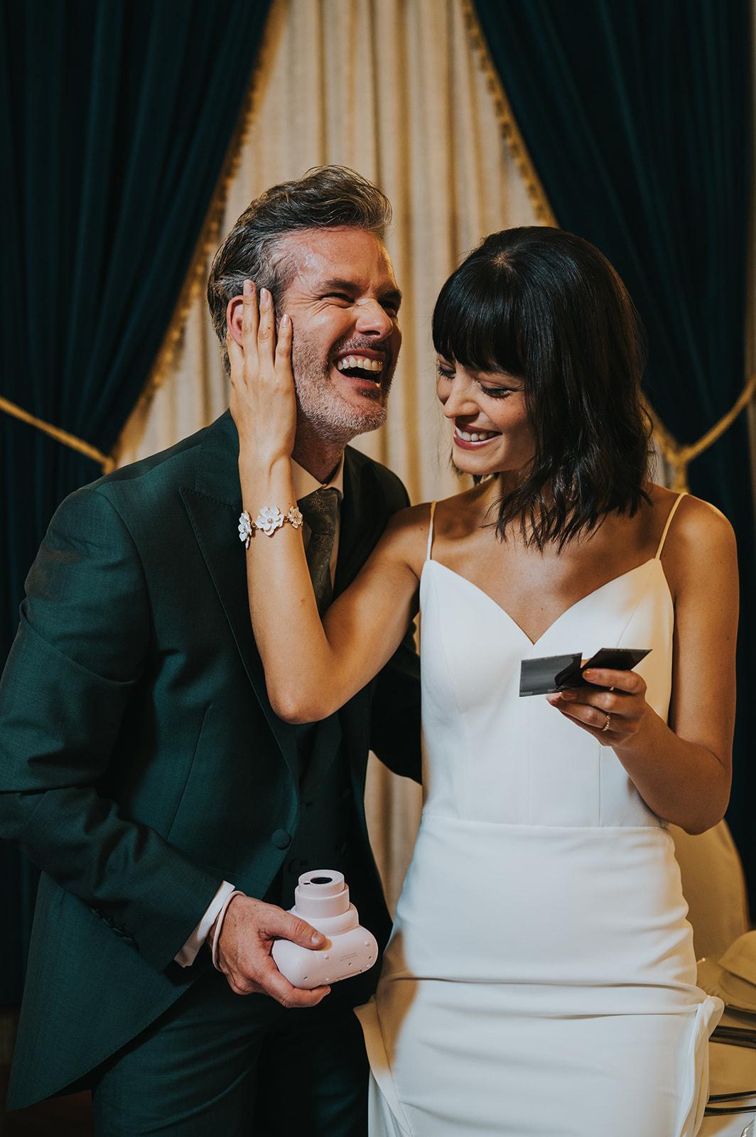 sposi sorridenti che tengono in mano una fotocamera istantanea e le polaroid per nozze dallo stile Y2K