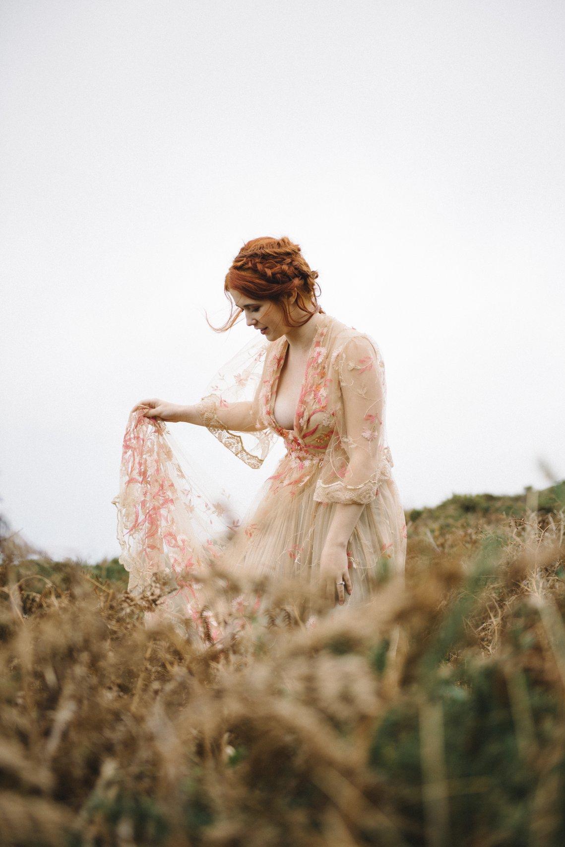 sposa con abito da sposa in pizzo rosa con ricami floreali in mezzo alla campagna- stili matrimonio