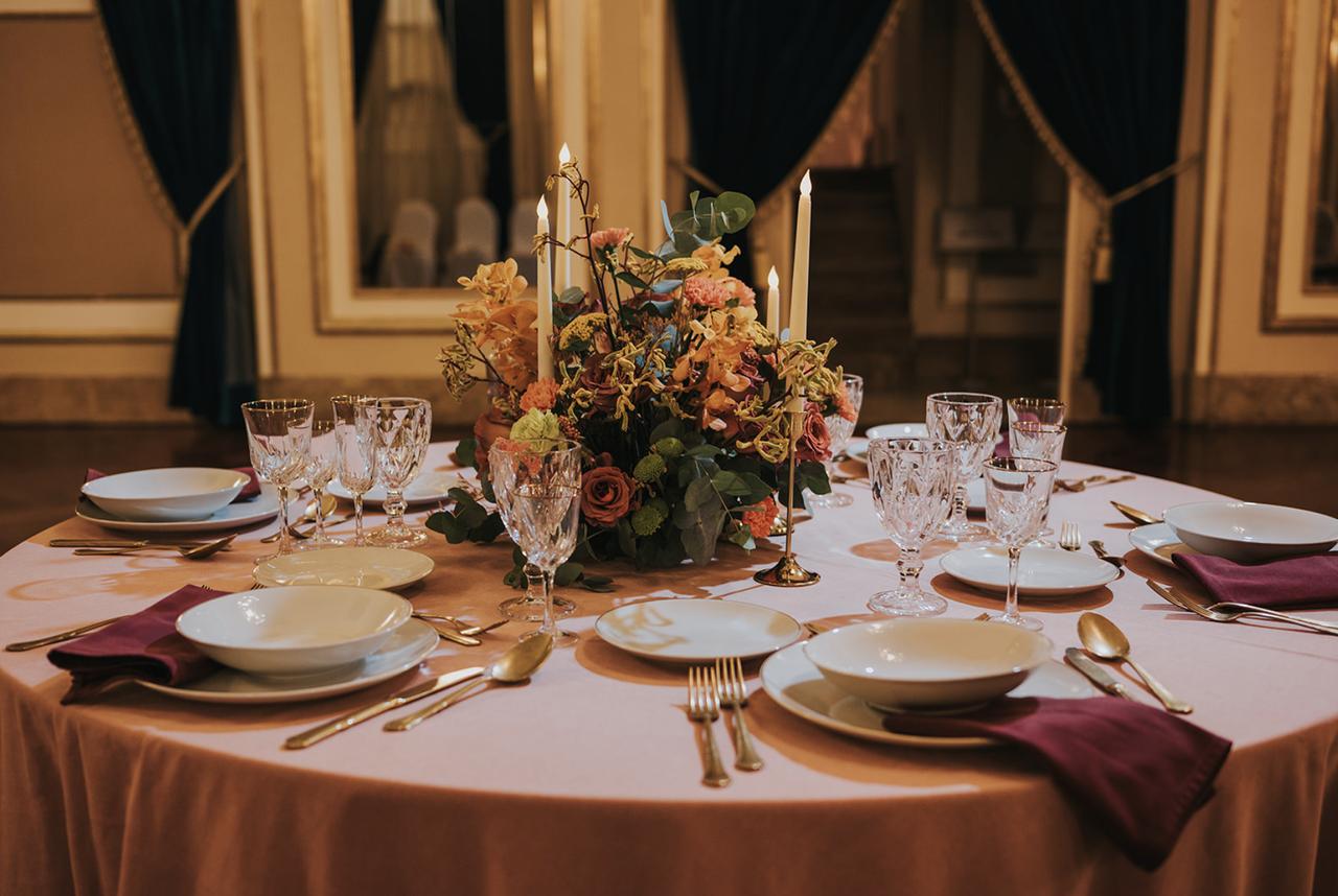 mise en place per matrimonio in stile regency con centrotavola floreale, tovaglia rosa e porcellane bianche e eoro