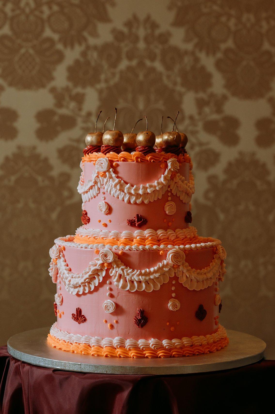 torta nuziale in stile regency a più piani con decori a drappeggio e ciliegie a guarnire