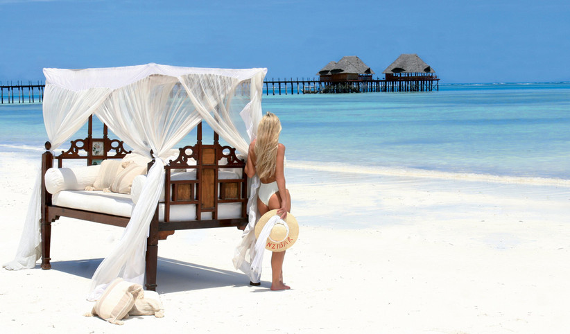spiaggia maldiviana con palafitte e ragazza che guarda il mare