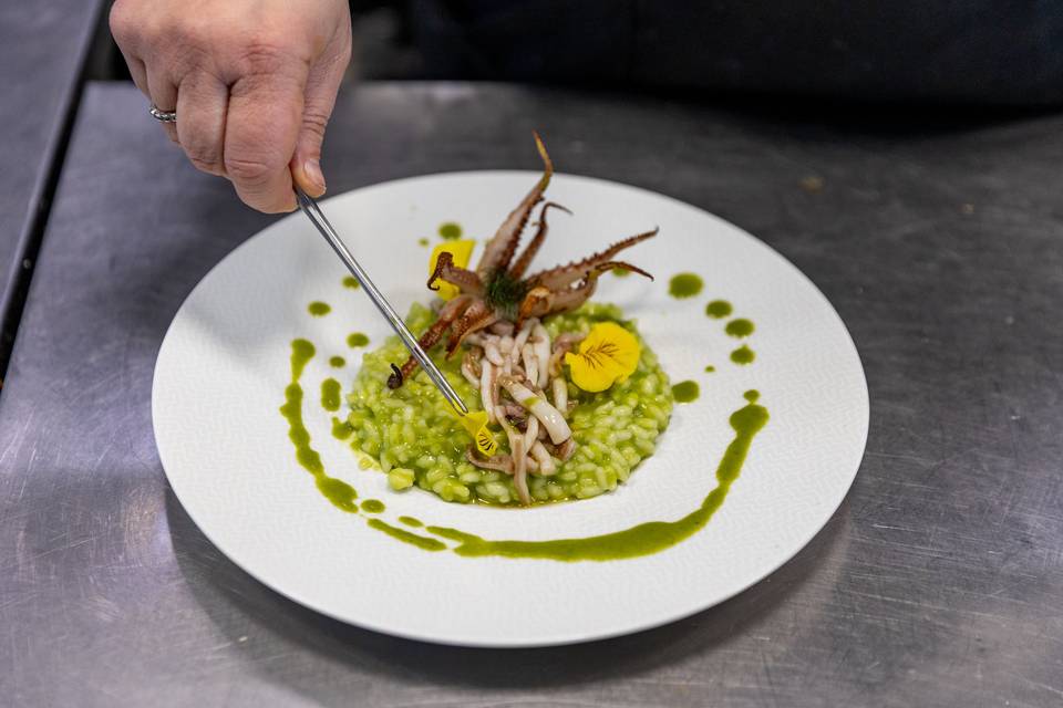 chef posiziona polpo su risotto verde