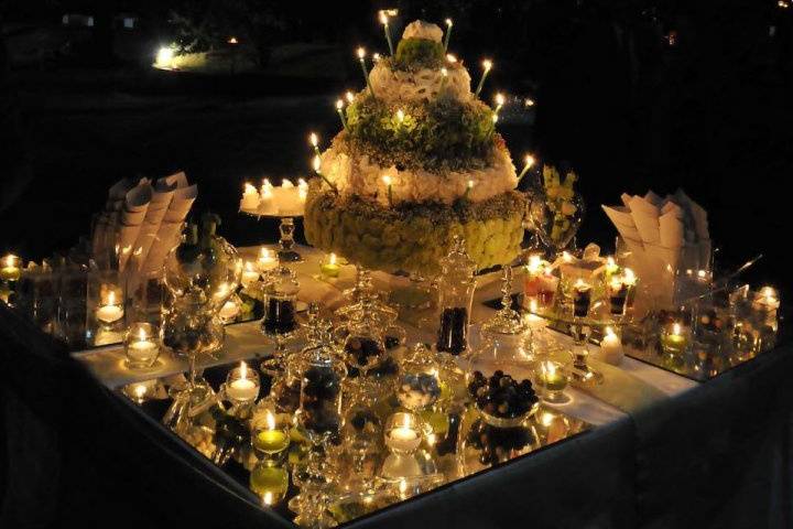 Mise en place del buffet con finta torta fiorita con candele, specchi e allestimenti