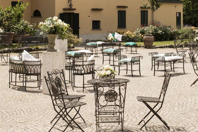 L'attesa degli ospiti, fra le rose e i tavolini del cortile