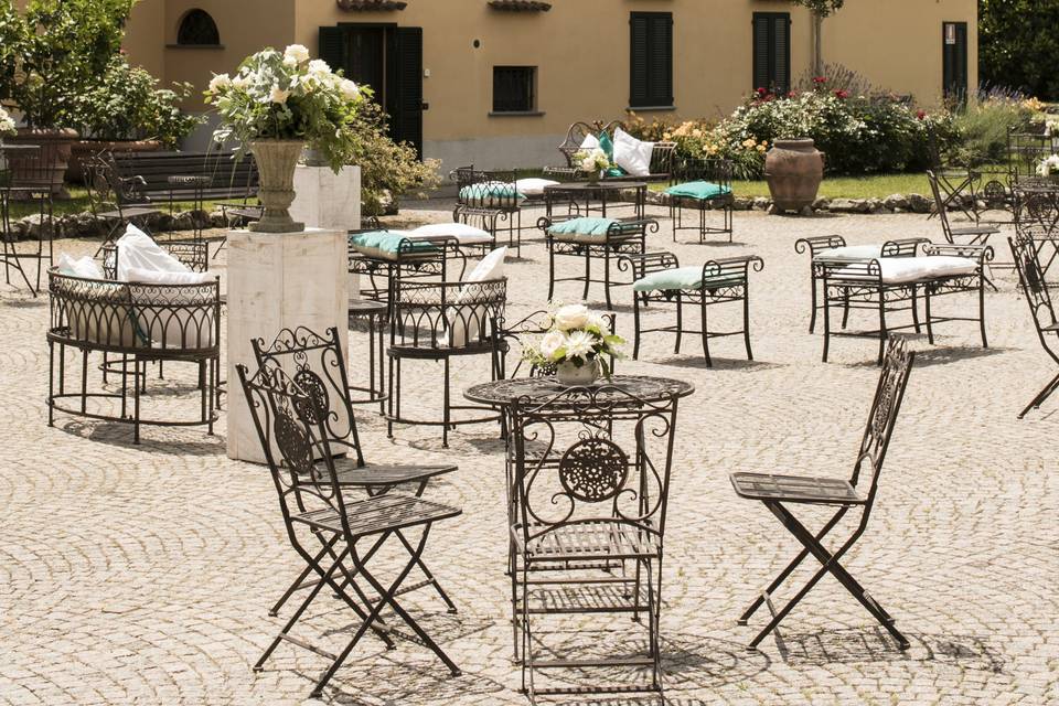 L'attesa degli ospiti, fra le rose e i tavolini del cortile