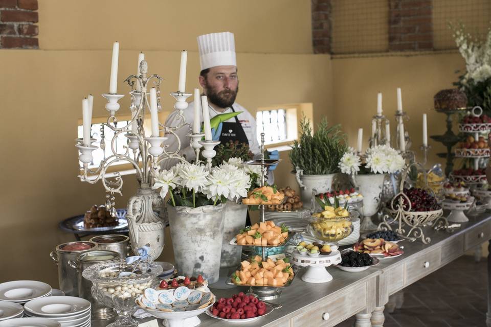 Frutta fresca, candelabri d'argento, mani esperte